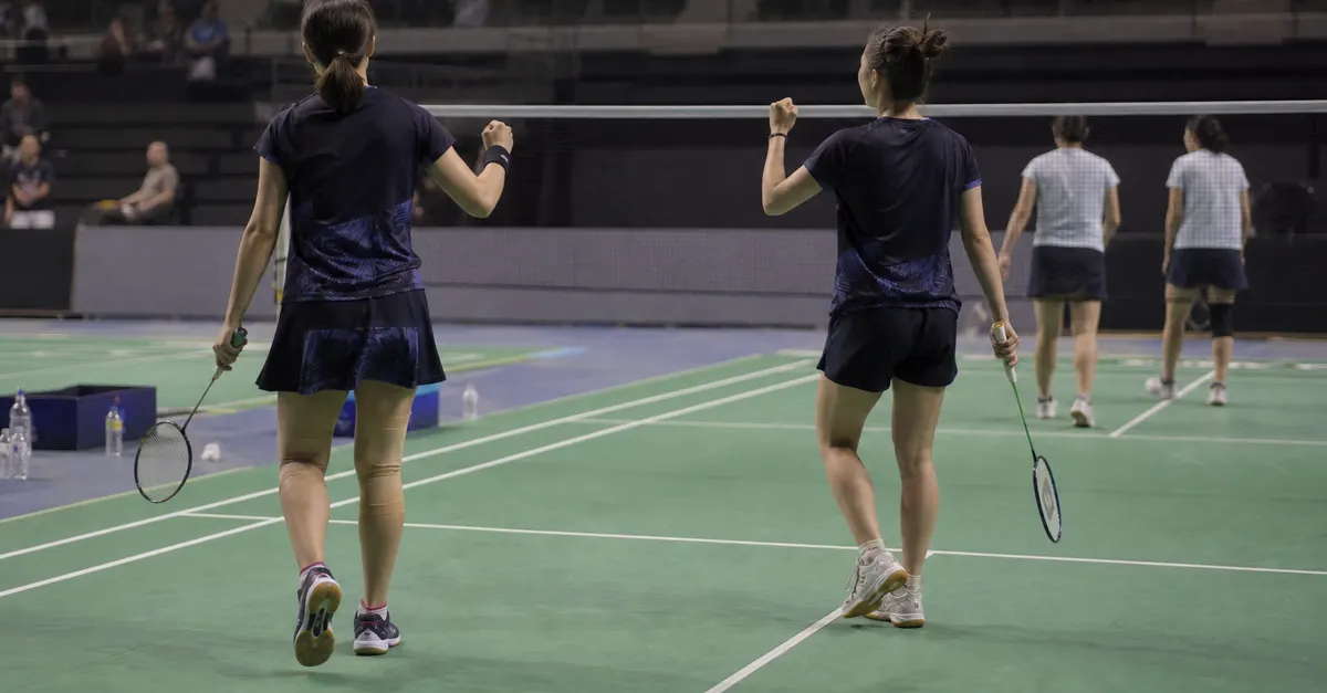 Two badminton players celebrate reaching a final on an indoor court.