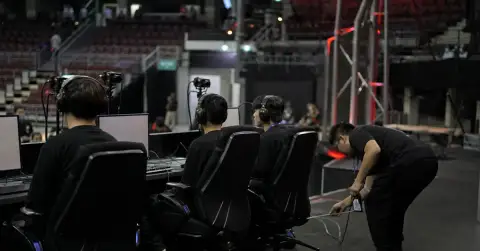 Anonymous esports players prepare at gaming PCs in a tournament arena.