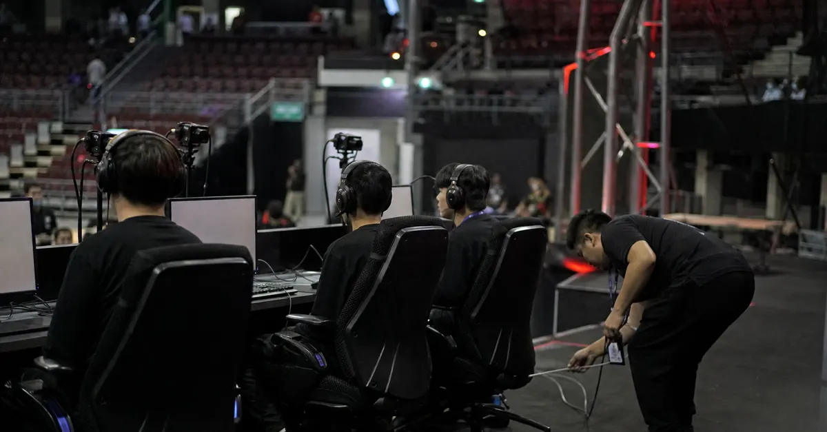 Anonymous esports players prepare at gaming PCs in a tournament arena.