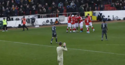 Anonymous goalkeeper applauds teammates after a hard-fought away win