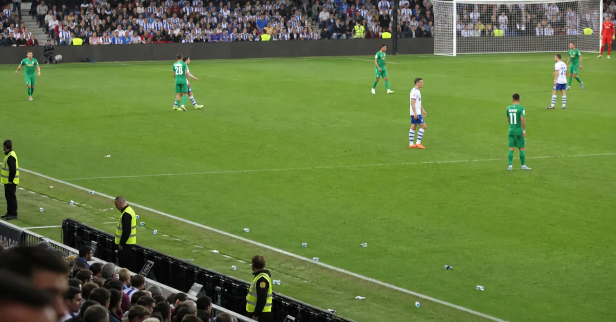 Football match halted as scattered objects lie near the touchline