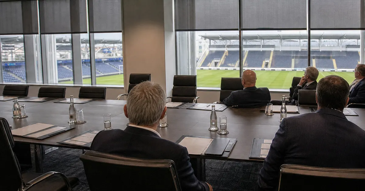 Anonymous football executives meet amid empty chairs and folders