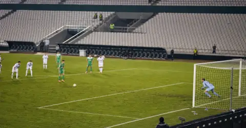 Anonymous players contest a tense football match in an empty stadium.