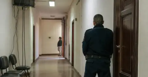 A quiet courthouse corridor with security outside a closed courtroom.
