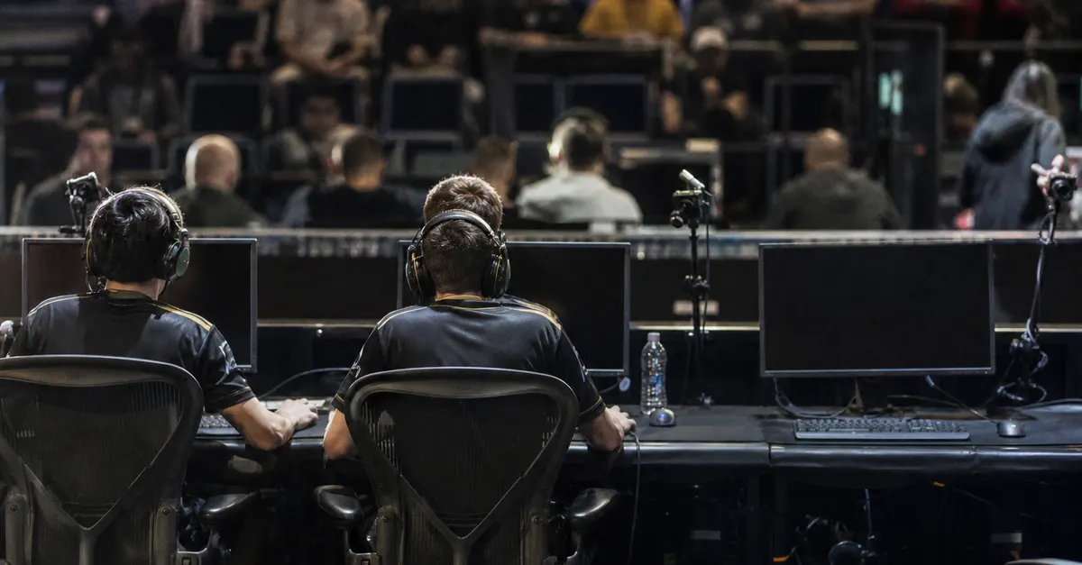 Two esports players join teammates at gaming PCs in an arena