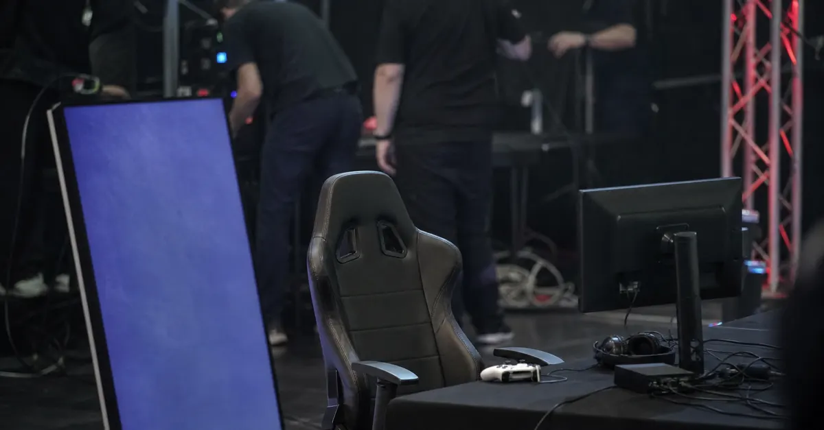 Empty esports stage with gaming station and blank promotional display.