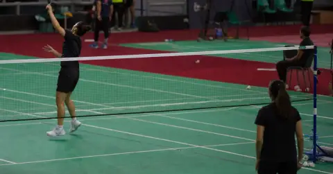 Two badminton players warm up as teammates watch courtside in Cairo.