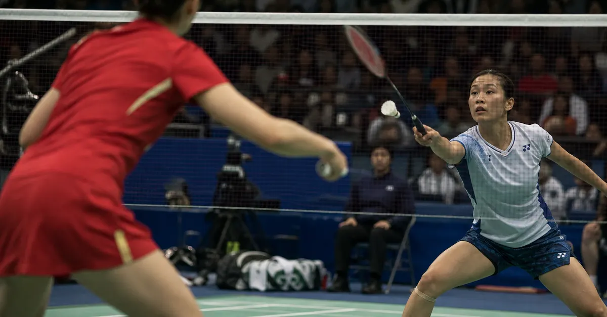 Two badminton players prepare for a rally across the net.