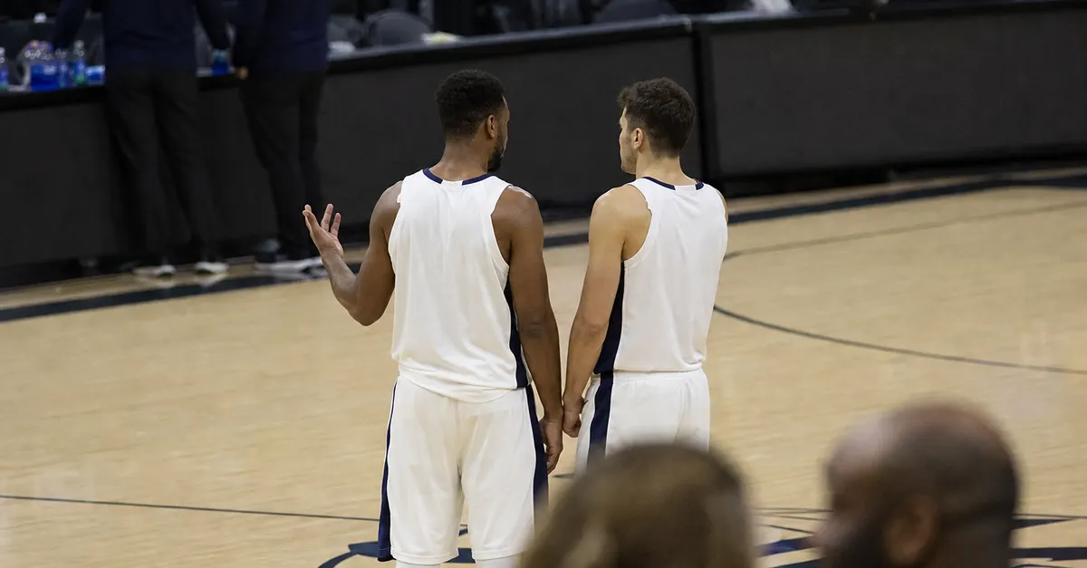 Two anonymous basketball teammates talk courtside after a close game.
