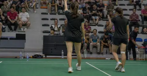 A badminton player acknowledges supporters after a tournament-ending doubles defeat.