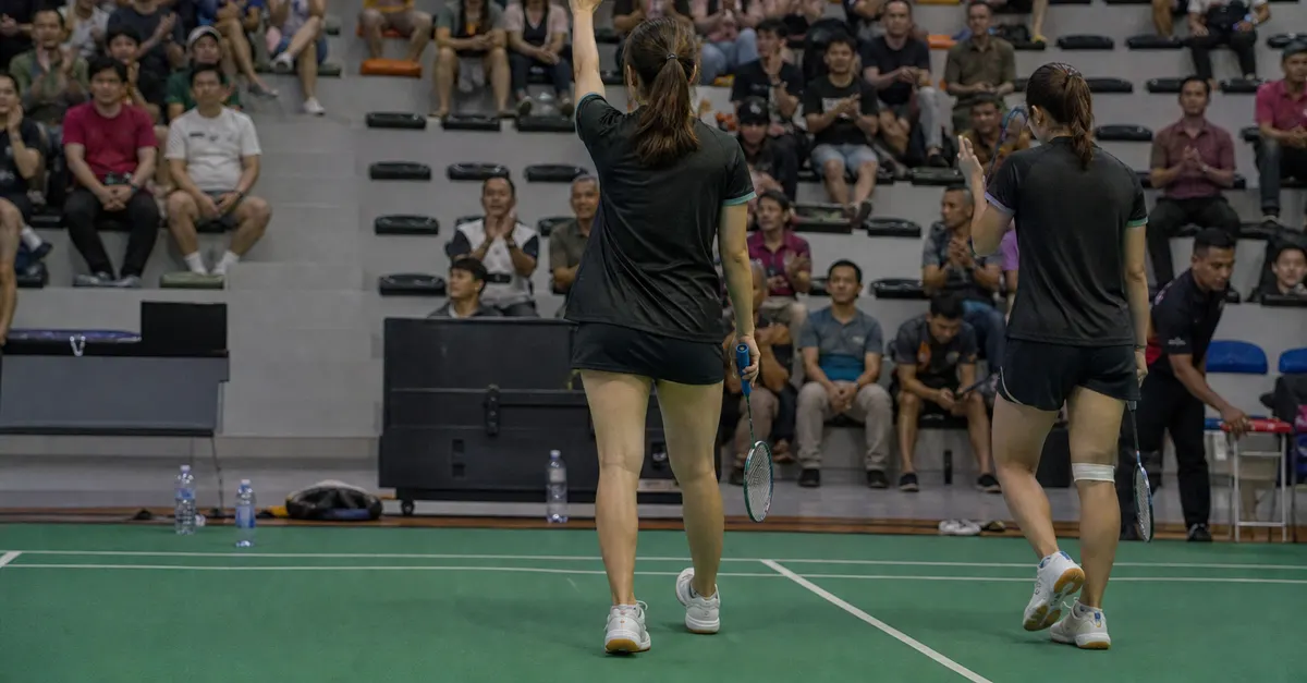 A badminton player acknowledges supporters after a tournament-ending doubles defeat.
