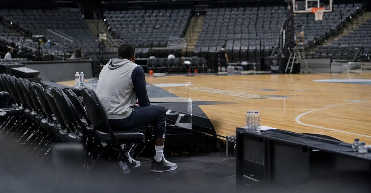 An anonymous basketball player sits courtside during a quiet practice.