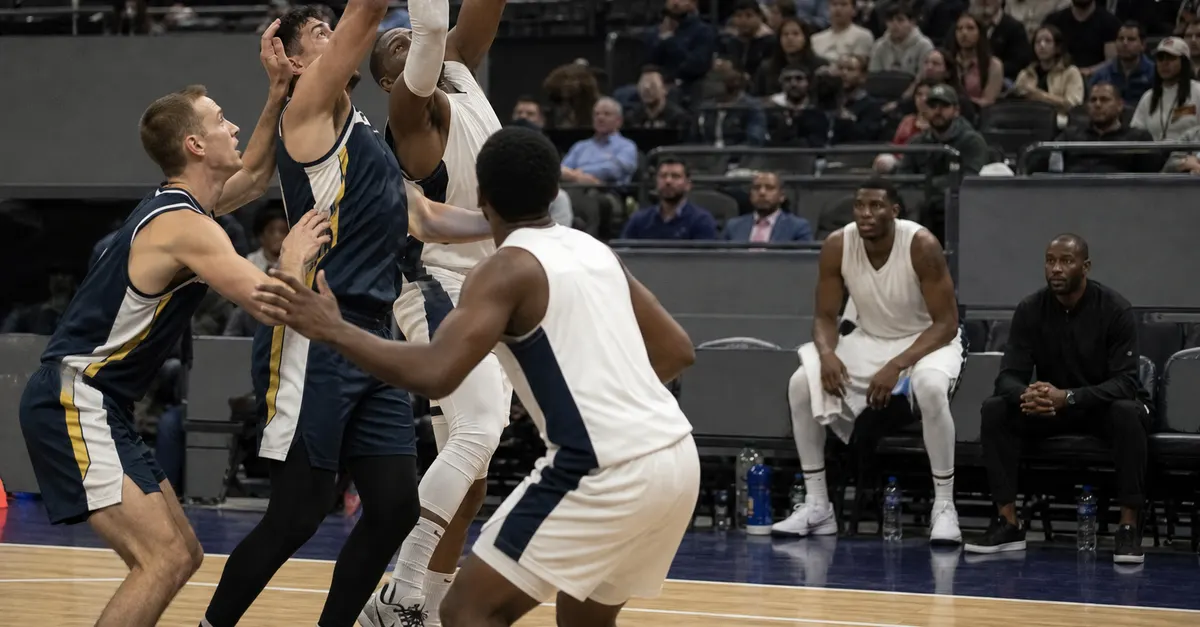 Anonymous basketball players compete as a sidelined teammate watches from the bench.