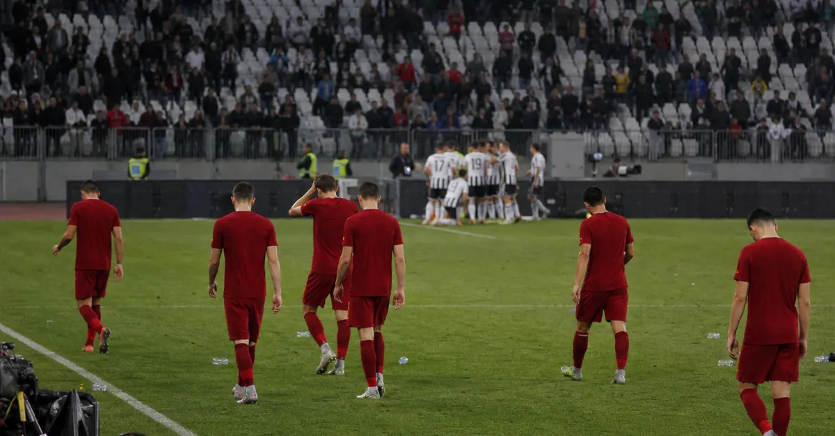Dejected red-shirted players leave as opponents celebrate after a football match