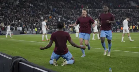 Anonymous footballers celebrate a European night victory at a packed stadium.