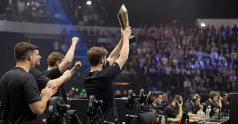 Anonymous esports players celebrate a tournament win beside gaming PCs.