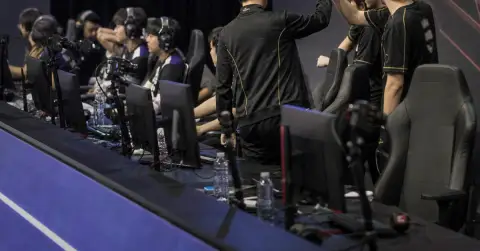 Anonymous esports players celebrate beside gaming PCs after a tournament match.