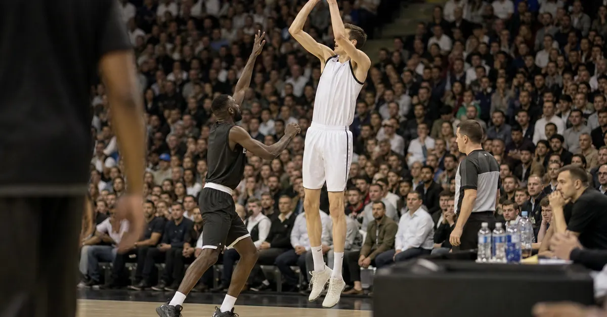 A towering basketball player rises for a shot during a crowded game.