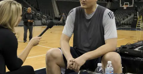 Anonymous tall basketball player speaks calmly during a courtside interview.