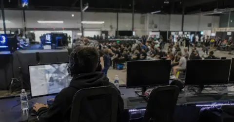 A focused esports player competes at a LAN event amid arena lights.